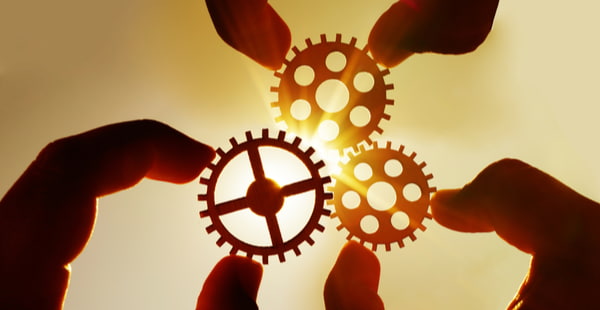 Male hand holding three wooden cog gear