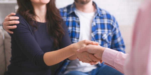 Thankful couple handshaking with specialist