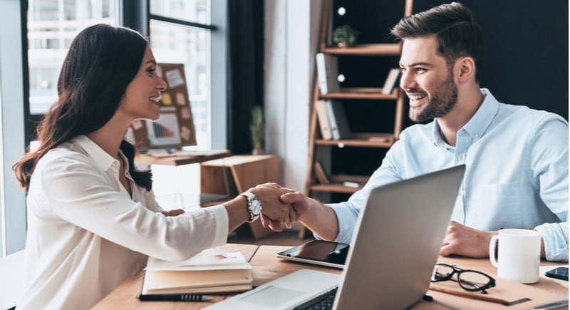 Young modern colleagues in smart casual wear shaking hands