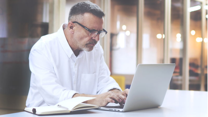 Mature businessman in eye glasses using his laptop