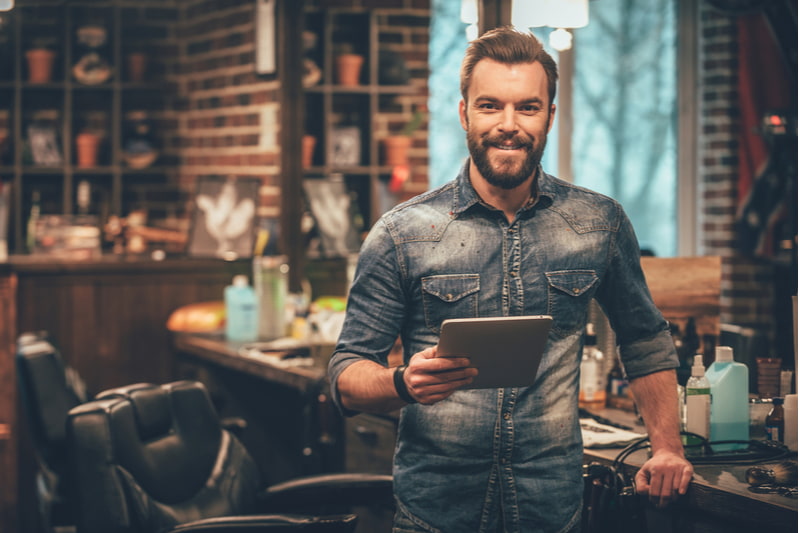 Bearded man looking at camera and holding digital tablet